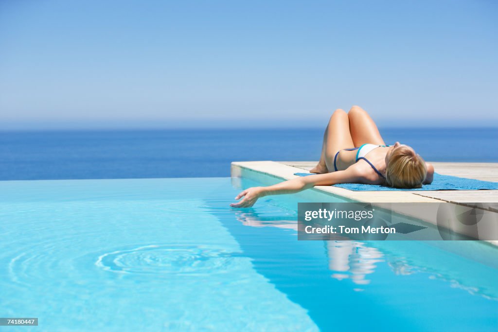 Woman sunbathing on deck with infinity pool