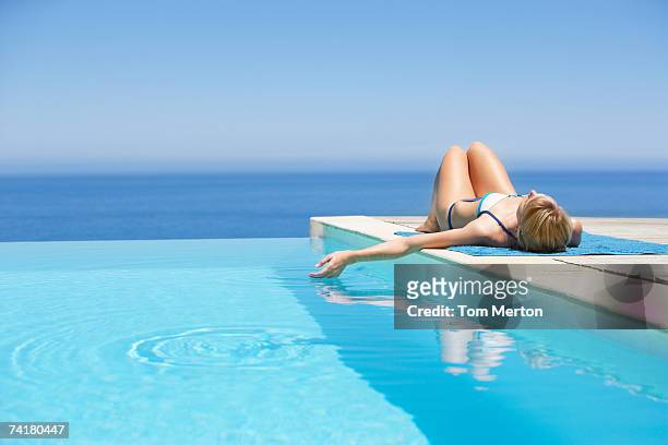 woman sunbathing on deck with infinity pool - resort pool stock pictures, royalty-free photos & images