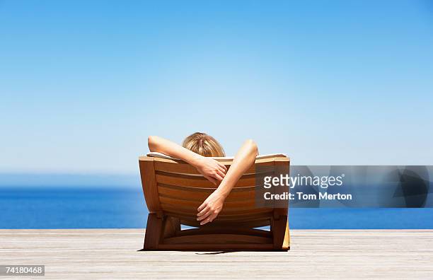 vista posteriore della donna sdraiato sulla sedia pieghevole all'aperto - ambientazione tranquilla foto e immagini stock
