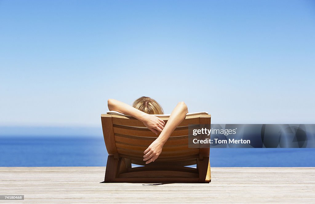 Rear view of woman reclining on folding chair outdoors