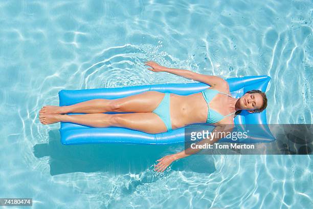 woman in bikini on flotation device in pool - women sunbathing pool stock pictures, royalty-free photos & images