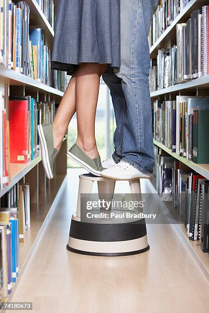 waist down woman and man standing on step stool in library - love books stock pictures, royalty-free photos & images