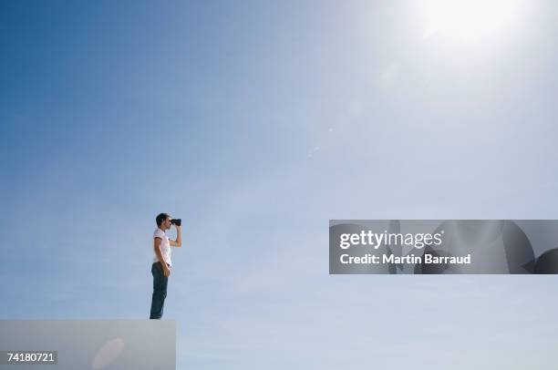 un homme sur un piédestal avec des jumelles et ciel bleu en plein air - paire de jumelles photos et images de collection