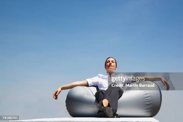 businesswoman sitting on beanbag chair outdoors with eyes closed - beanbag chair stockfoto's en -beelden