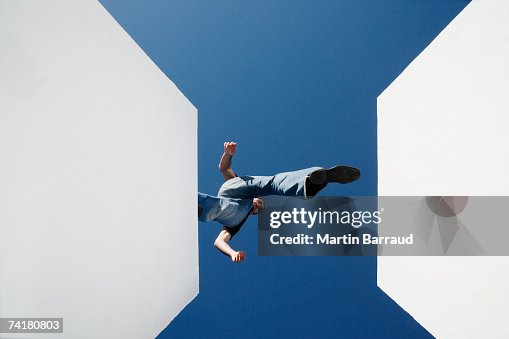 Low angle view of man walking across high gap outdoors Low angle view of man walking across high gap outdoors