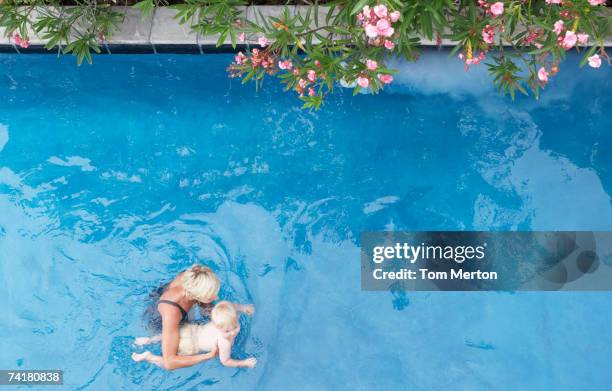 mother with baby in pool with flowers - mother and baby taking a bath stock pictures, royalty-free photos & images