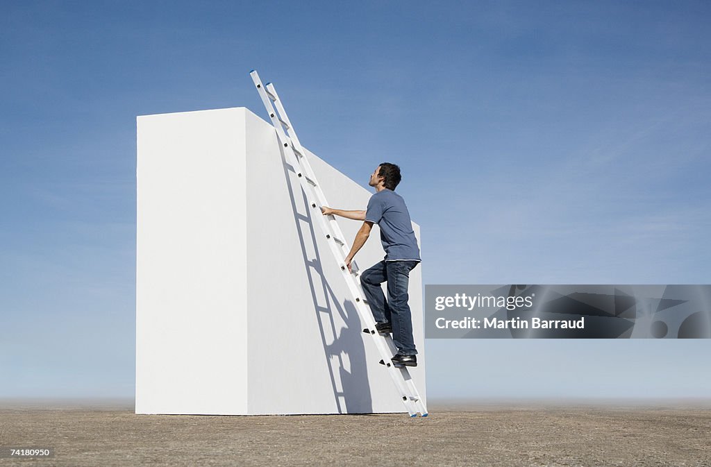 Man climbing ladder against wall outdoors