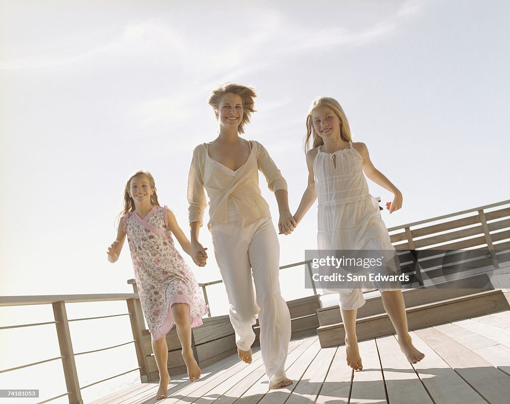 Woman and girls holding hands and smiling outdoors