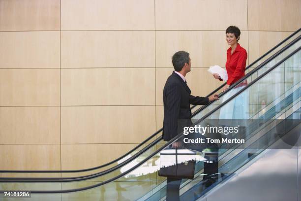 homme d'affaires et femme d'affaires sur l'escalier roulant - escalator photos et images de collection