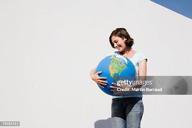 woman embracing globe and smiling outdoors - one world stockfoto's en -beelden