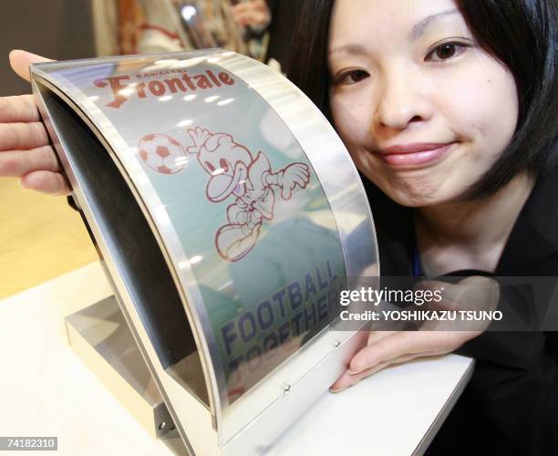 Japan's computer giant Fujitsu employee displays the prototype model of an electronic paper display that is flexible and does not blur even if it is...