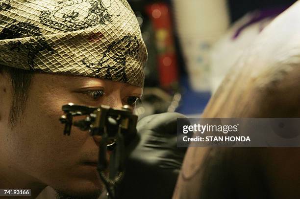 New York, UNITED STATES: Taiwanese tattoo artist who identified himself as Lee of Assassin Tattoo in Taipei works on the back of Charlie Lee of...