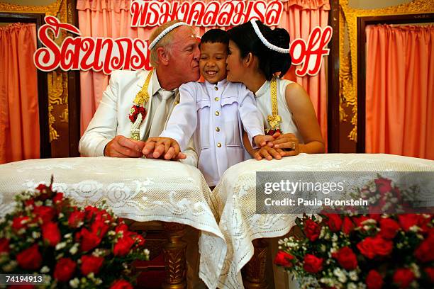 British groom Geoffrey Goodwin kisses his new stepson, Sorawi along side his Thai bride Ratanaporn at their traditional Thai wedding ceremony May 19,...