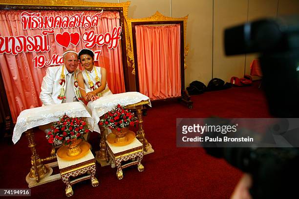 Wedding photographer shoots portraits of British groom Geoffrey Goodwin with his Thai bride Ratanaporn at their traditional Thai wedding ceremony May...