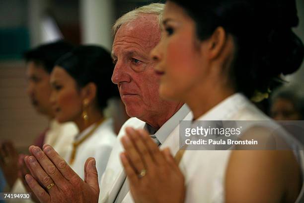British groom Geoffrey Goodwin prays along side his Thai bride Ratanaporn at their traditional Thai wedding ceremony May 19, 2007 in Bangkok,...