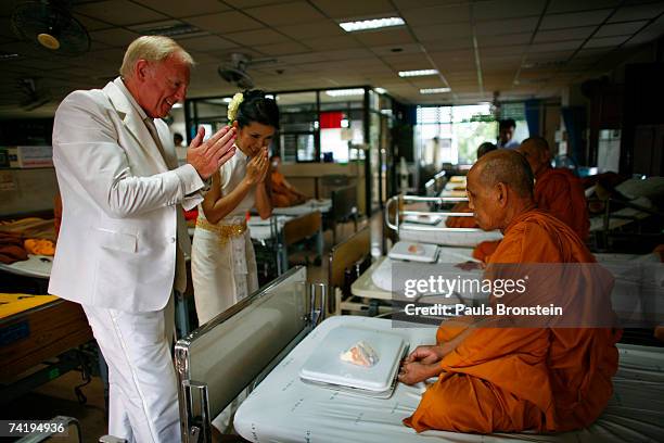 British groom Geoffrey Goodwin and his Thai bride Ratanaporn greet monks before their traditional Thai wedding ceremony May 19, 2007 in Bangkok,...