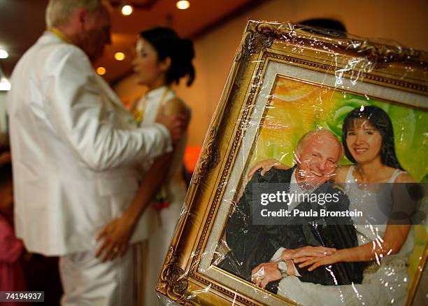 British groom Geoffrey Goodwin holds his Thai bride Ratanaporn next a painting of the couple durign a traditional Thai wedding ceremony May 19, 2007...