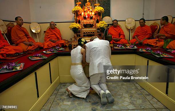 British groom Geoffrey Goodwin kneels, giving prayer to monks along side his Thai bride Ratanaporn during their traditional Thai wedding ceremony May...