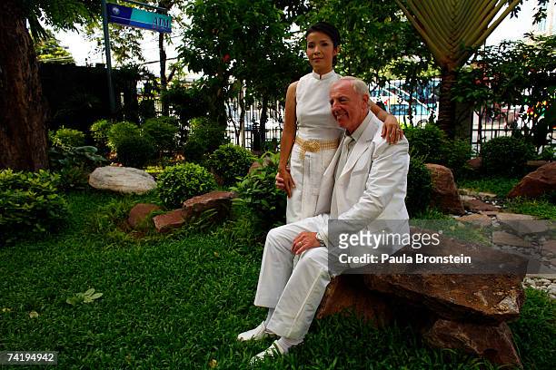 British groom Geoffrey Goodwin sits with his Thai bride Ratanaporn near an ATM bank machine moments after their traditional Thai wedding ceremony May...