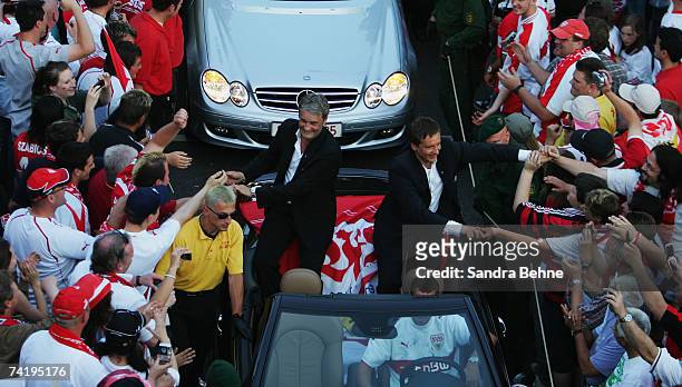 Coach Armin Veh and manager Horst Heldt of VfB Stuttgart shake hands with fans during a car convoy after winning the German championships after the...