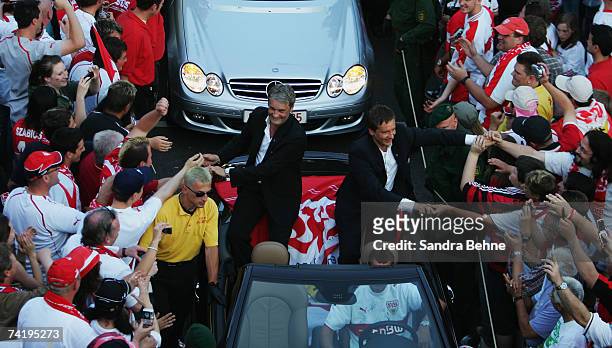 Coach Armin Veh and manager Horst Heldt of VfB Stuttgart shake hands with fans during a car convoy after winning the German championships after the...