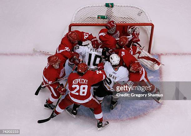 Corey Perry and Brad May of the Anaheim Ducks are surrounded by members of the Detroit Red Wings as they crash into goalie Dominik Hasek of the Red...