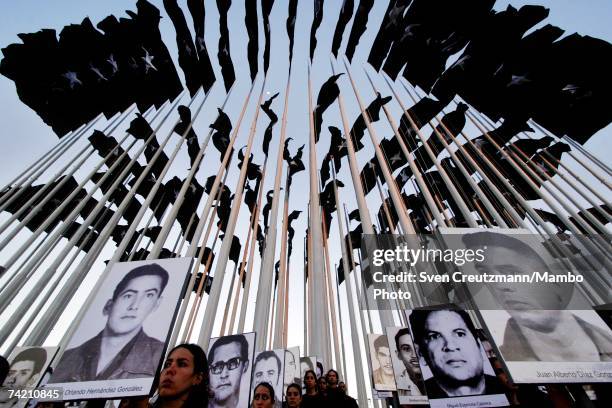 Young Cuban students hold up photographs of Cuban terrorist victims during the inauguration of the "Plaza De Las Banderas", a display of 138 black...