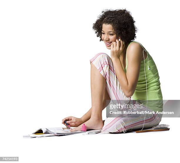 teenage girl with braces talking on cell phone and painting toenails - black painted toes stock-fotos und bilder