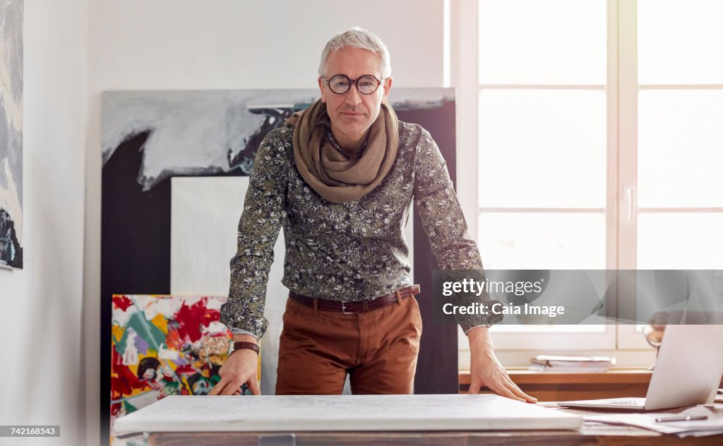 Portrait confident male photographer standing over canvas in art studio