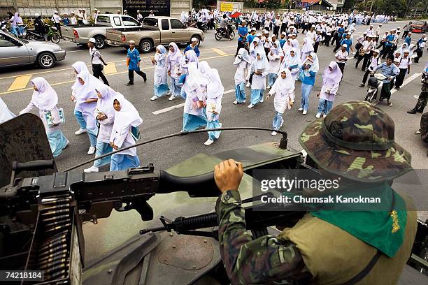 Thai muslim students walk across the street as Thai soldiers provide protection in Nhong-Jit District May 22 Pattani province, Thailand. More than...