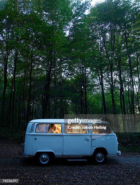 "family in illuminated van in forest, side view, evening" - road trip van stock pictures, royalty-free photos & images