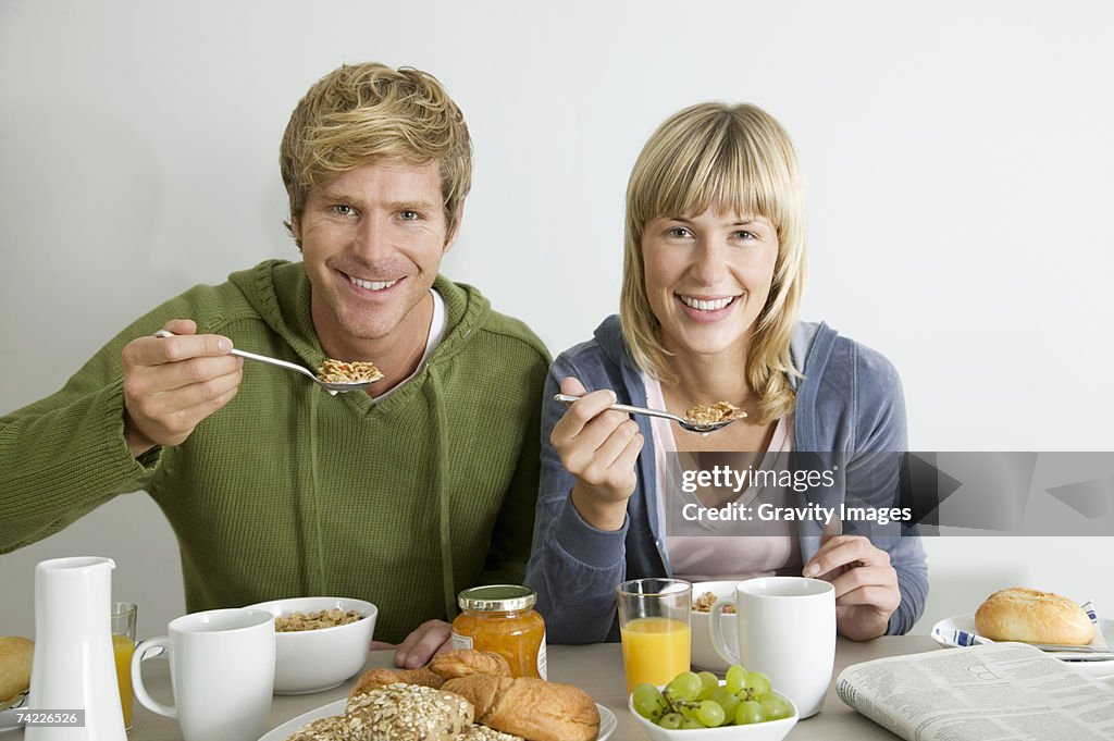 Couple eating breakfast at dining table, portrait