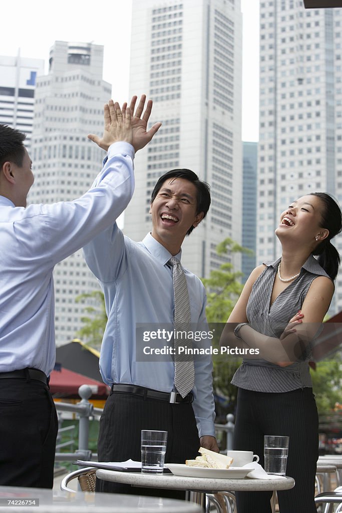 Businesspeople giving high five at outdoors cafe