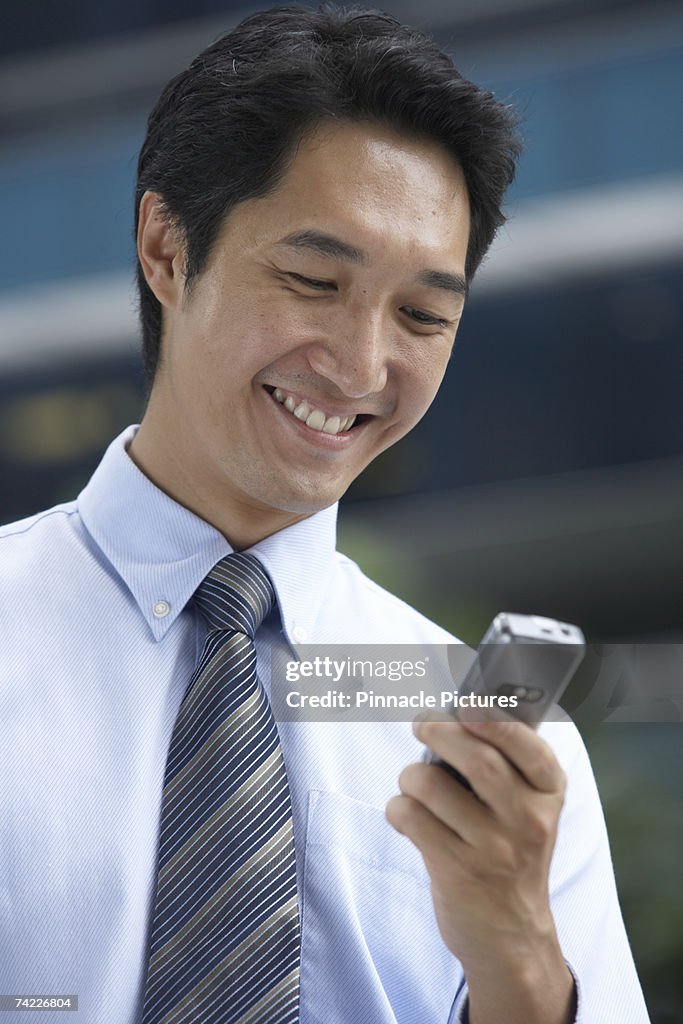 Smiling businessman looking at mobile phone