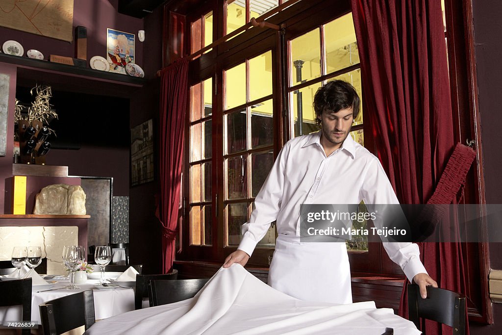 Waiter laying table in restaurant