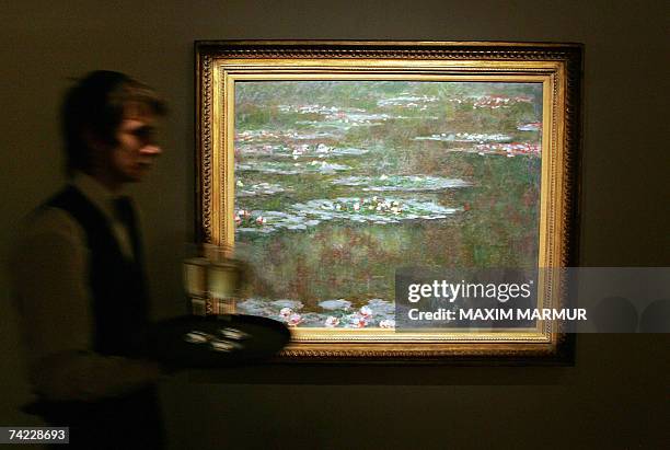 Moscow, RUSSIAN FEDERATION: A waiter passes by "Nympheas" by French impressionist painter Claude Monet exhibited before a Sotheby's auction in the...