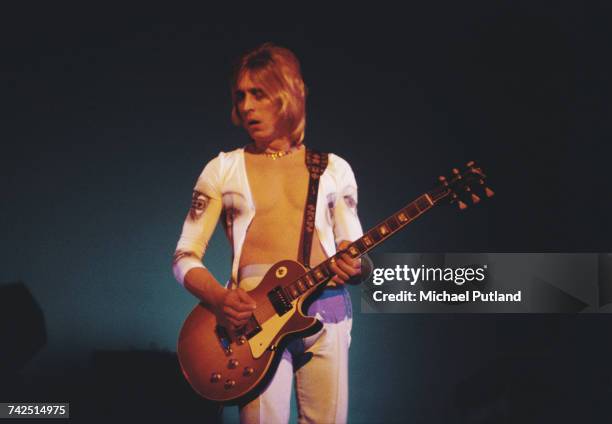 English rock musician and guitarist Mick Ronson performs live on stage playing a Gibson Les Paul guitar with Ian Hunter at the Hammersmith Odeon in...