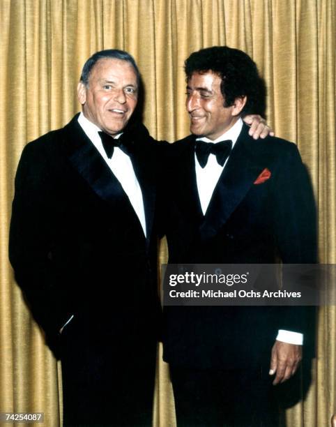 Pop singers Tony Bennett and Frank Sinatra pose for a portrait wearing tuxedos in front a of a gold curtain in July of 1980 in Reno, Nevada.