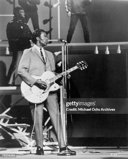 Rock and roll guitarist Chuck Berry performs his 'duck walk' as he plays his electric hollowbody guitar at the TAMI Show on December 29, 1964 at the...