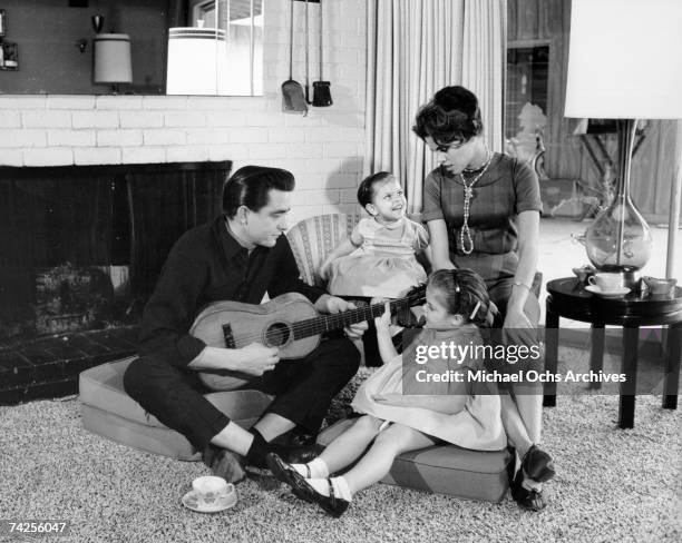 Country singer/songwriter Johnny Cash holds a guitar as his wife Vivian Liberto and daughters, Rosanne Cash and Kathy Cash look on in 1957.