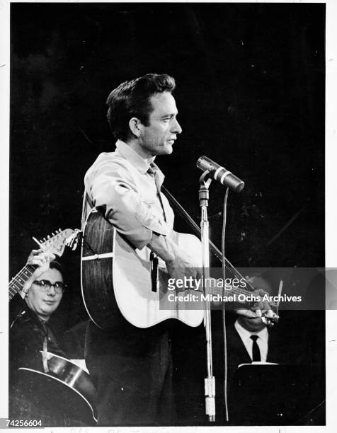 Country singer/songwriter Johnny Cash plays acoustic guitar as he performs onstage in circa 1965.