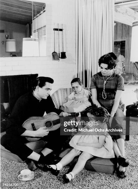 Country singer/songwriter Johnny Cash holds a guitar as his wife Vivian Liberto and daughters, Rosanne Cash and Kathy Cash look on in 1957.