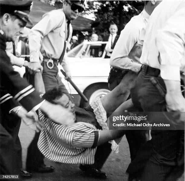 An African American woman is dragged away by policemen during a protest against segregation organized by Reverend Dr. Martin Luther King Jr. And...