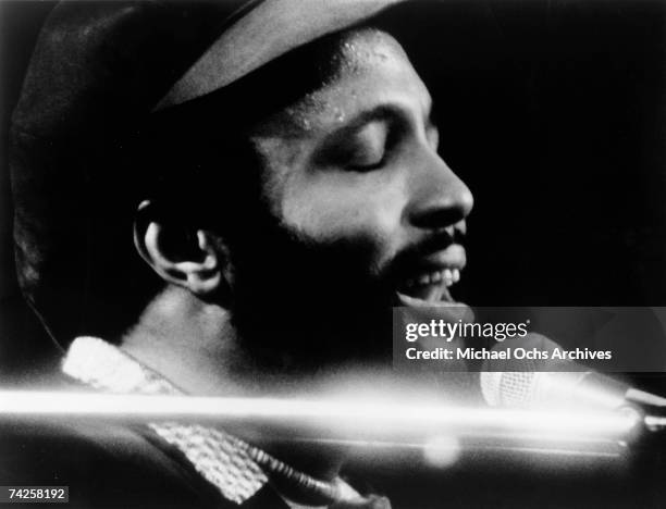 Singer and composer Andrae Crouch plays the piano as he sings in to a microphone in circa 1976.
