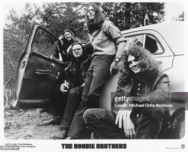 Pat Simmons, John Hartman, Dave Shogren and Tom Johnston of the rock and roll band "The Doobie Brothers" pose for a portrait with a car in circa 1970.