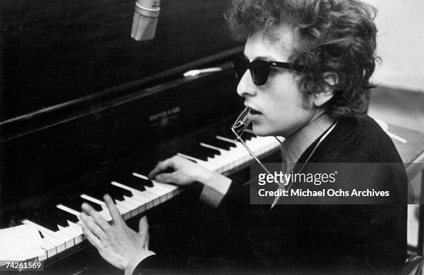 Bob Dylan plays piano with a harmonica around his neck during the recording of the album 'Highway 61 Revisited' in Columbia's Studio A in the summer...