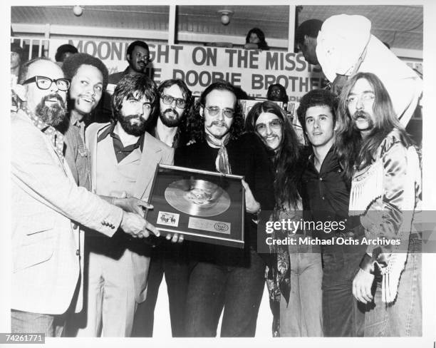 Warner Brothers chairman of the board Mo Ostin, gives a gold record to Tiran Porter, Mike McDonald, Keith Knudson, John Hartman, Patrick Simmons,...