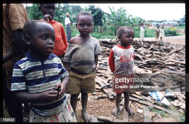 Children stand next to a pile of machetes that were used to kill Tutsis May 25, 1994 in Rwanda. Following the assassination of President Juvenal...