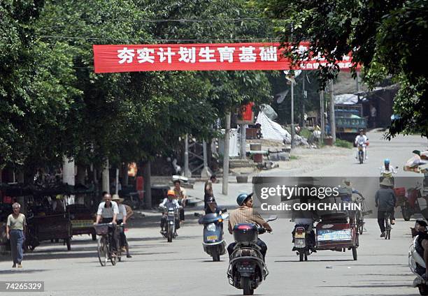 Bright red-and-white banner bearing government slogan "support the one-child policy" hangs across the road leading to the Bobai town government...