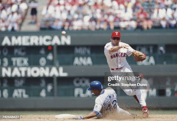 Bill Ripkin, Short Stop for the Texas Rangers throws to home as Bill Goodwin of the Kansas City Royals tries to slide into base during their Major...